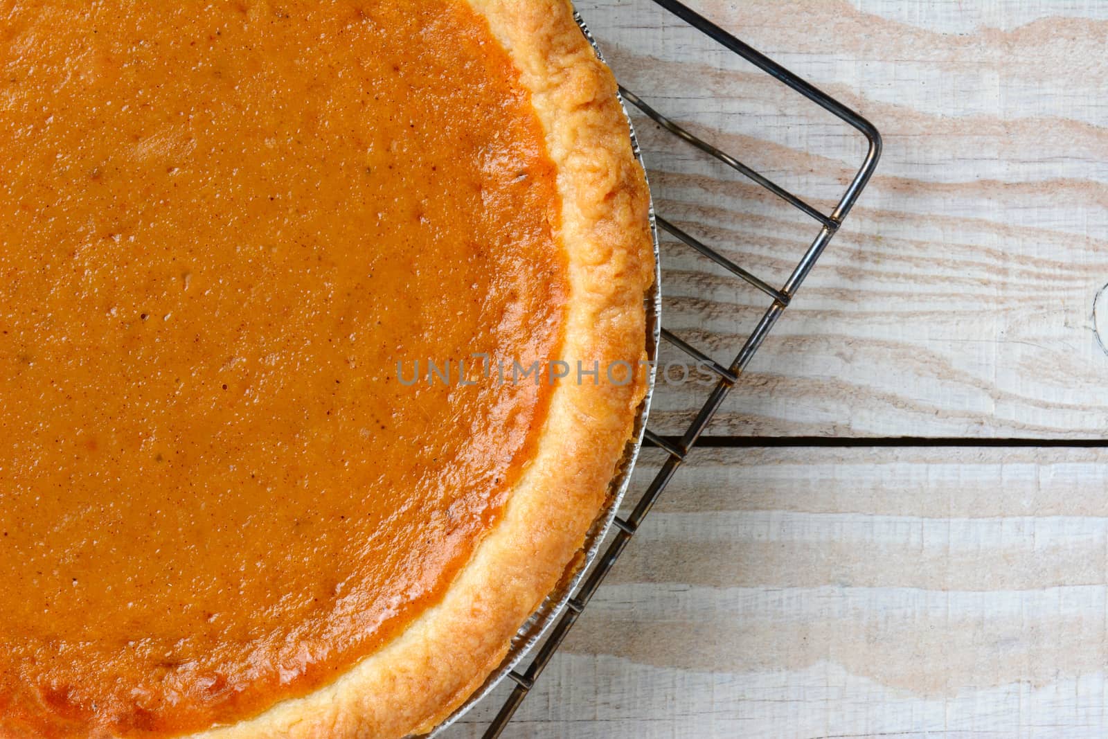 Closeup of a fresh baked pumpkin pie on a cooling rack. Horizontal format with copy space