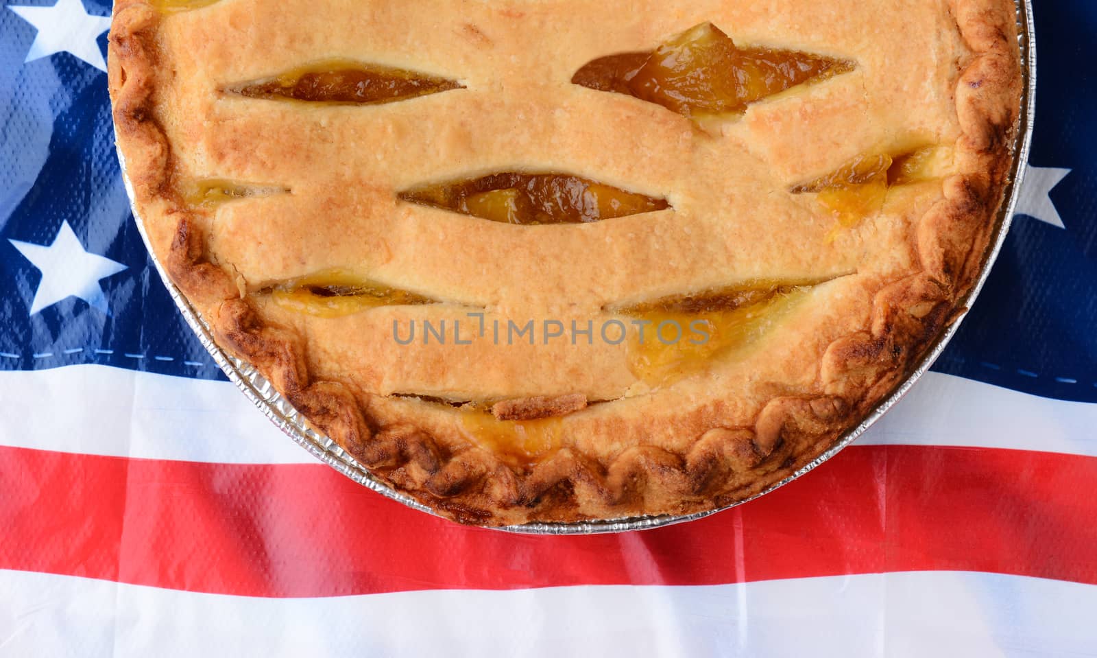 Overhead shot of a lattice top apple pie on an American Flag table cloth. Closeup only half of the pie is visible.