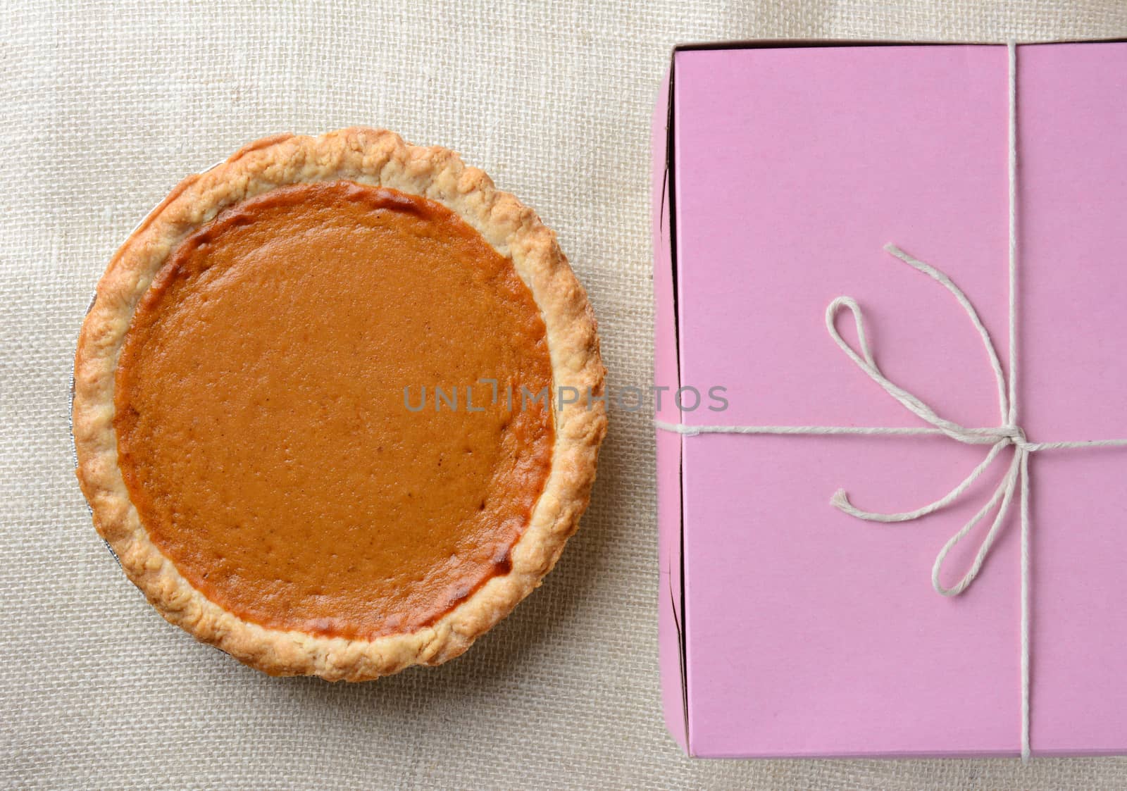 High angle shot of a holiday pumpkin pie and pink bakery box. Horizontal format.