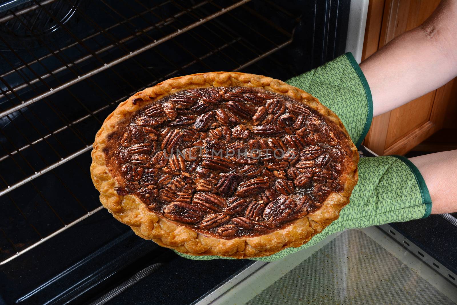 Closeup of a woman taking a fresh baked Pecan Pie from the oven. by sCukrov