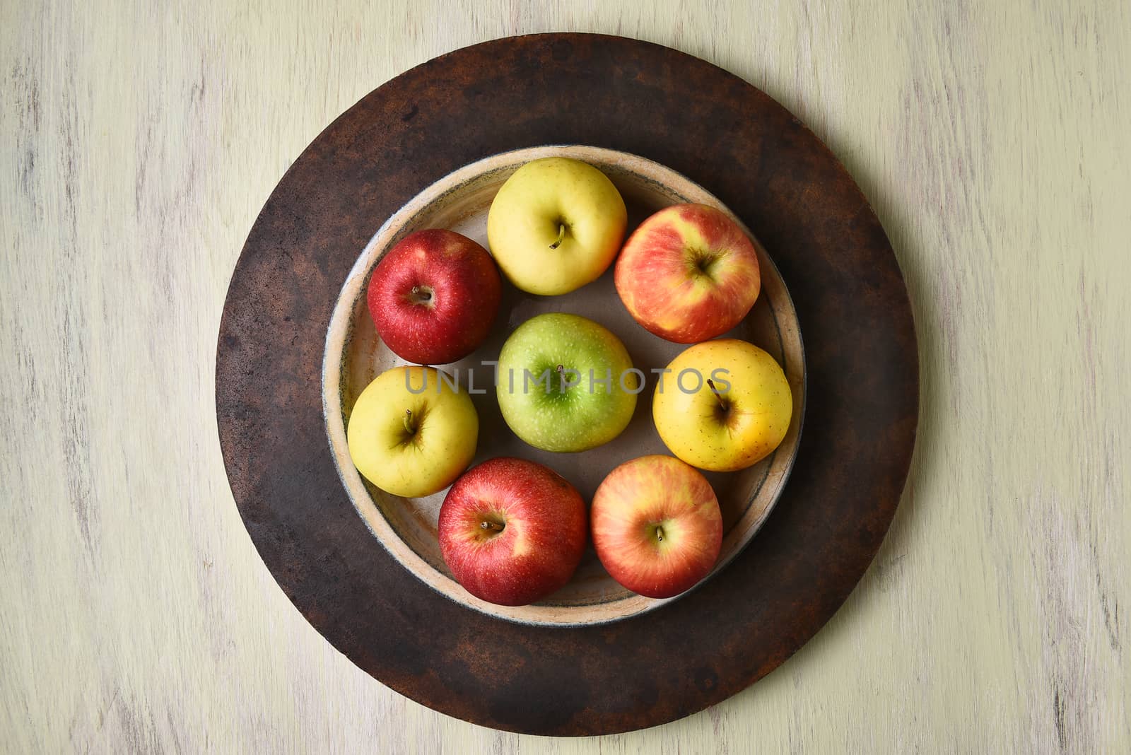 High angle view of a bowl of assorted apples on a rustic table.