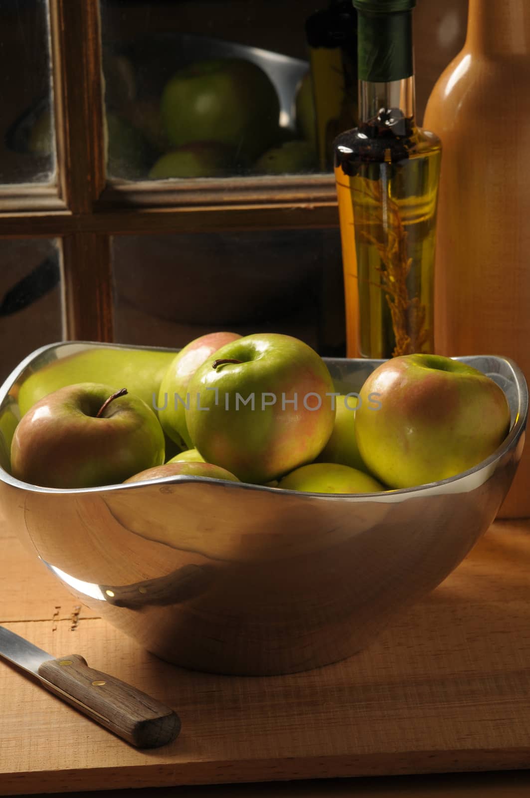 Bowl of Apples on rustic table top in front of window with strong side light vertical composition
