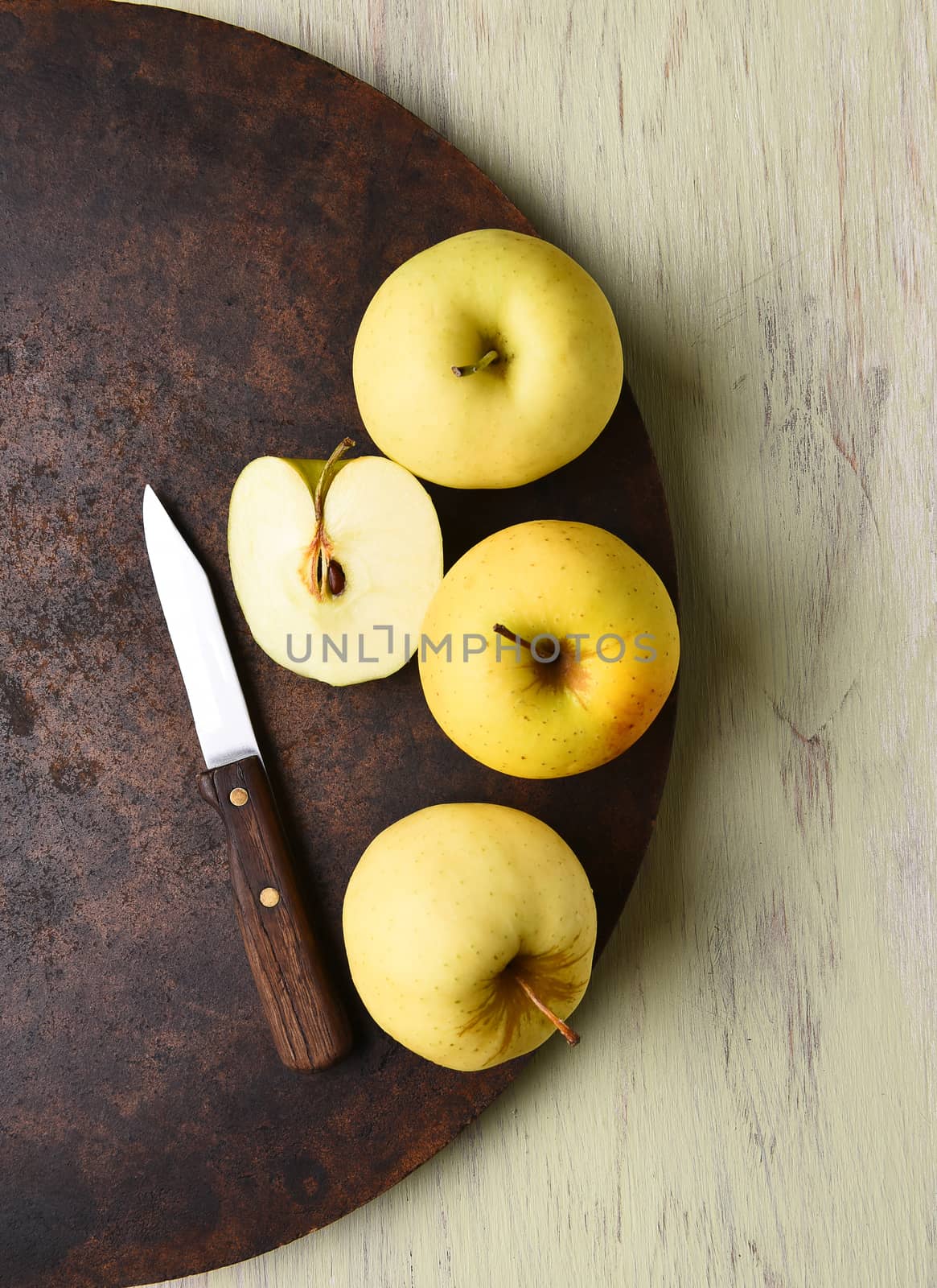 Golden Delicious apple still life with knife. Dark round surface on rustic table.