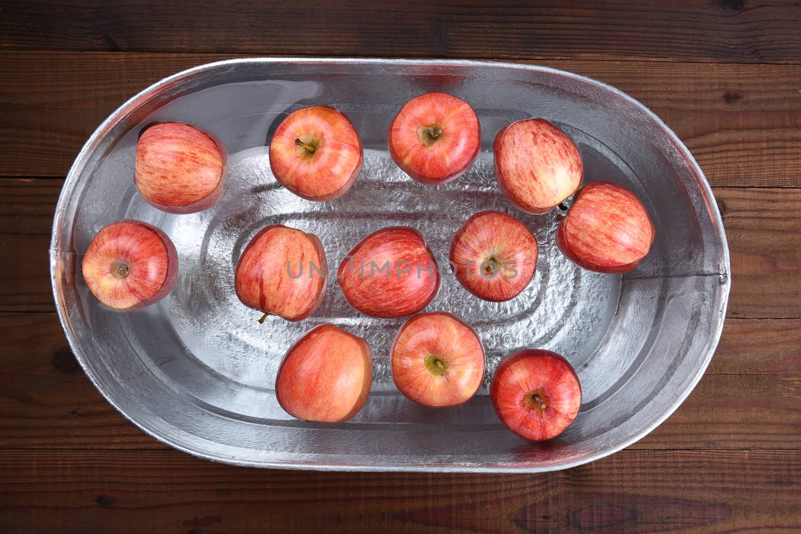 High angle horizontal shot of a metal tub filled with water and apples for the Halloween custom of Apple Bobbing.