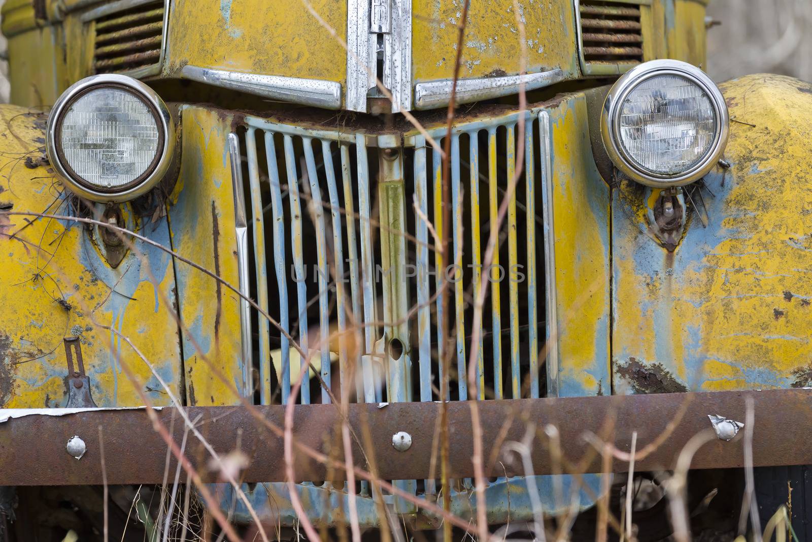 An old abandoned car sits in a field as it rusts away