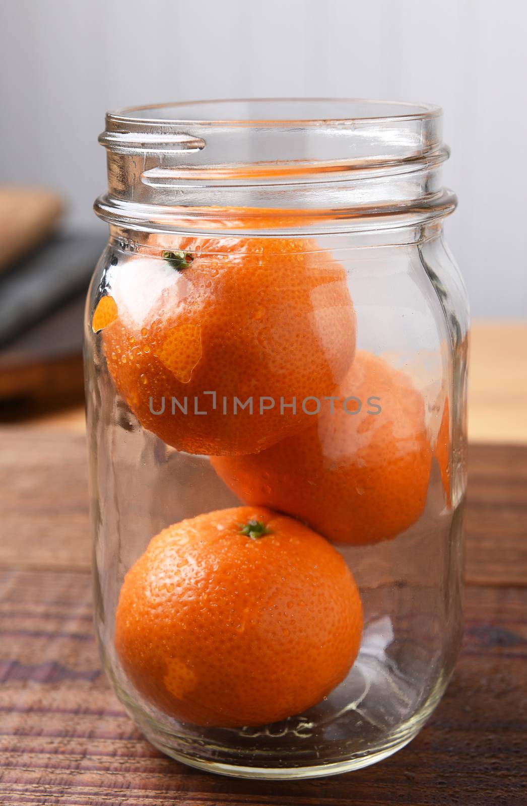 Closeup of a mason style jar with three whole Mandarin Oranges.