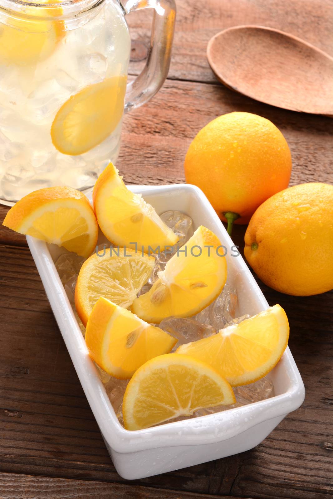 High angle shot of lemon slices in a white bowl on a rustic wooden kitchen table. 