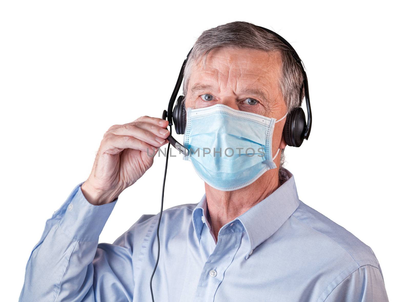 Senior caucasian man wearing facemask using headset to talk to customers or team during coronavirus epidemic. Isolated against white background