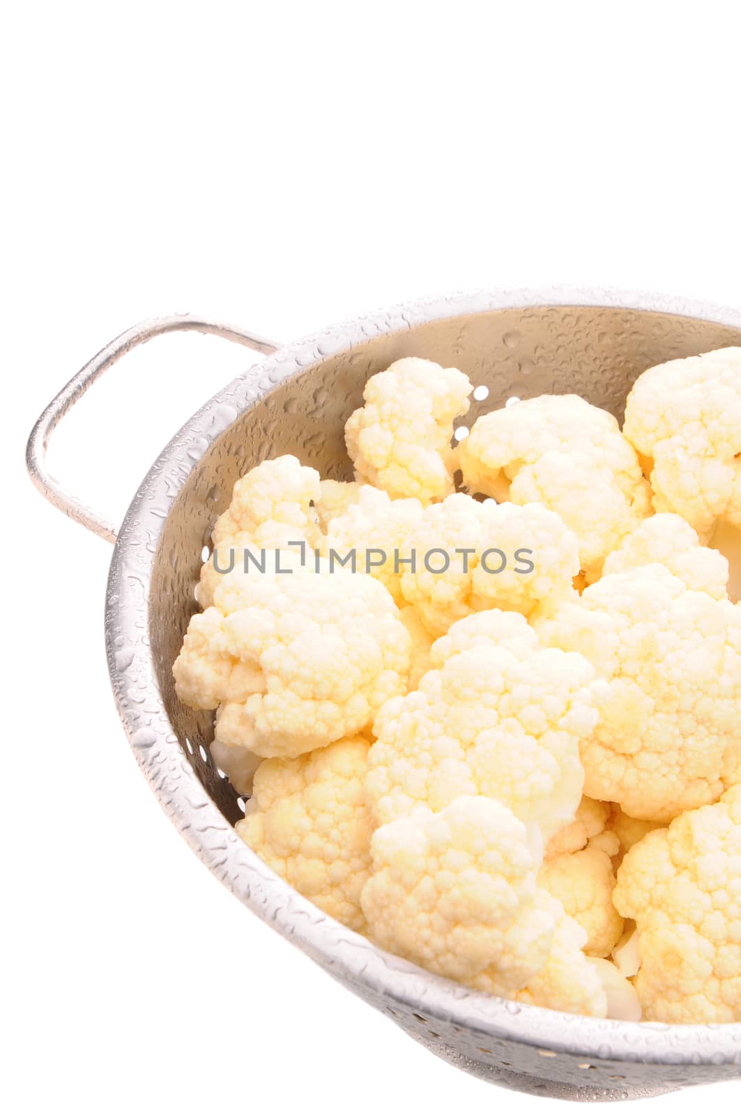 Closeup of cauliflower florets misted with water in a metal colander. Vertical Format isolated on white.