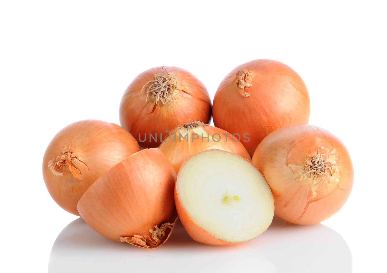 Closeup of a pile of yellow onions ona white surface with reflection. One onion is cut in half. Horizontal format.