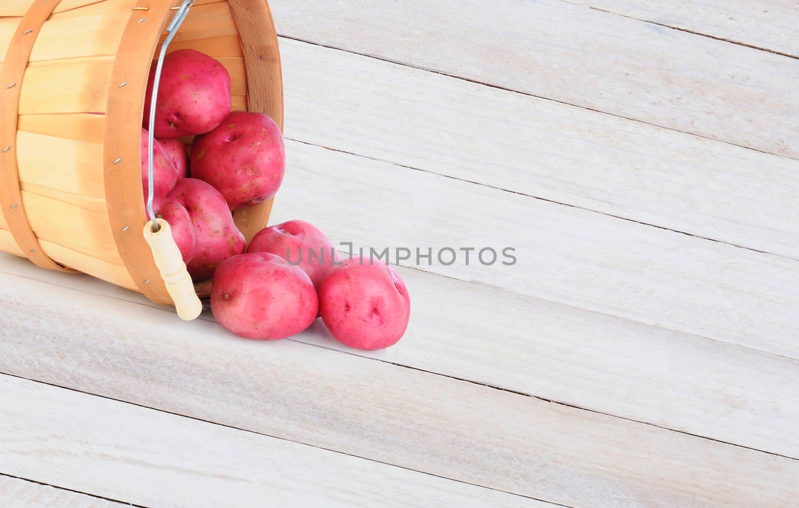 Potato Basket Spill on Wood Table by sCukrov