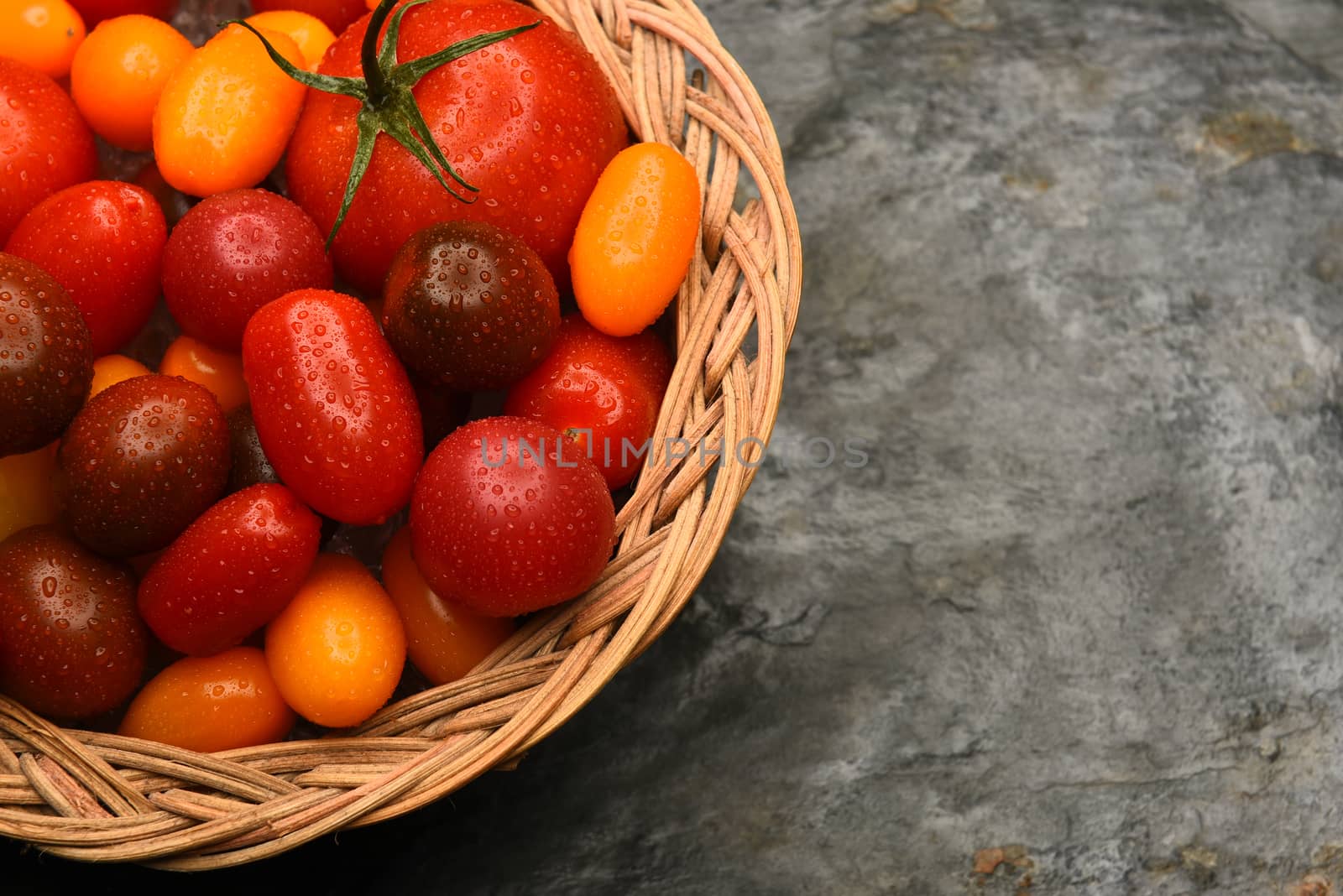 Top view of a basket filled with a variety of medley tomatoes. Horizontal format with copy space.