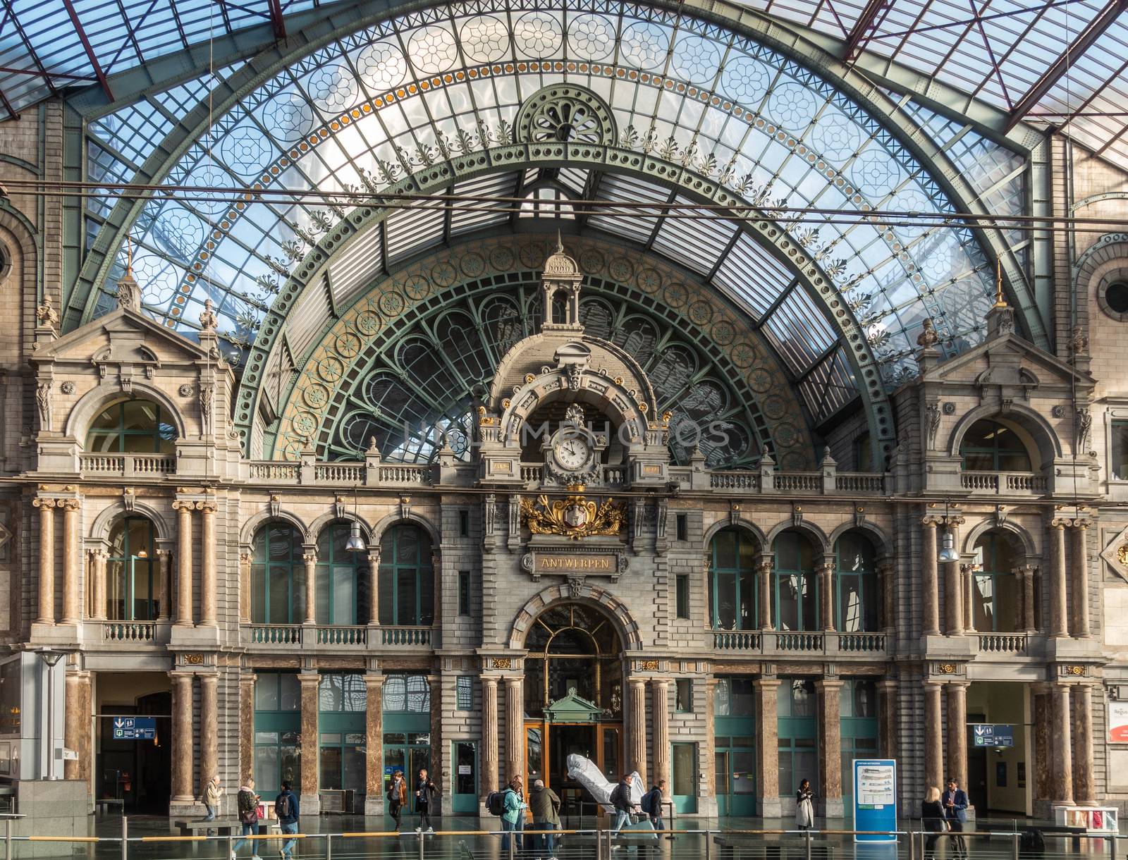 Antwerp, Belgium - September 24, 2018: Historic Train hall facade of Antwerpen Central Station, considered nicest train station in world. Glass roof, golden emblem, clock, facade and people.