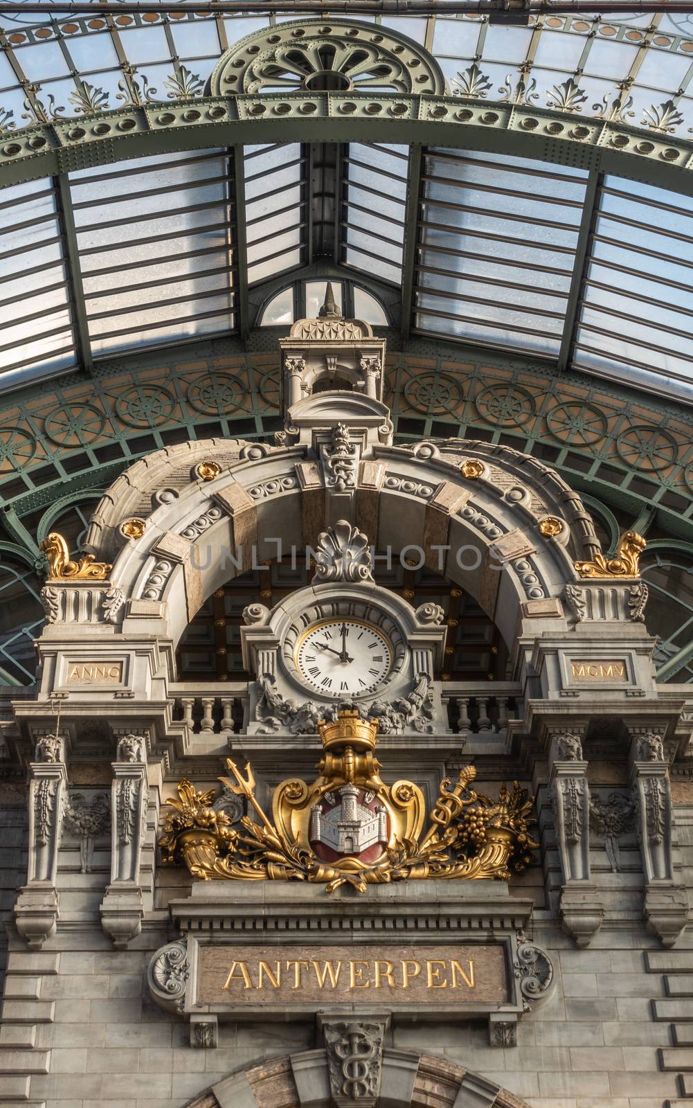 Antwerp, Belgium - September 24, 2018: Closeup of Clock and coat of arms of town on Train hall facade of Antwerpen Central Station. Glass roof.