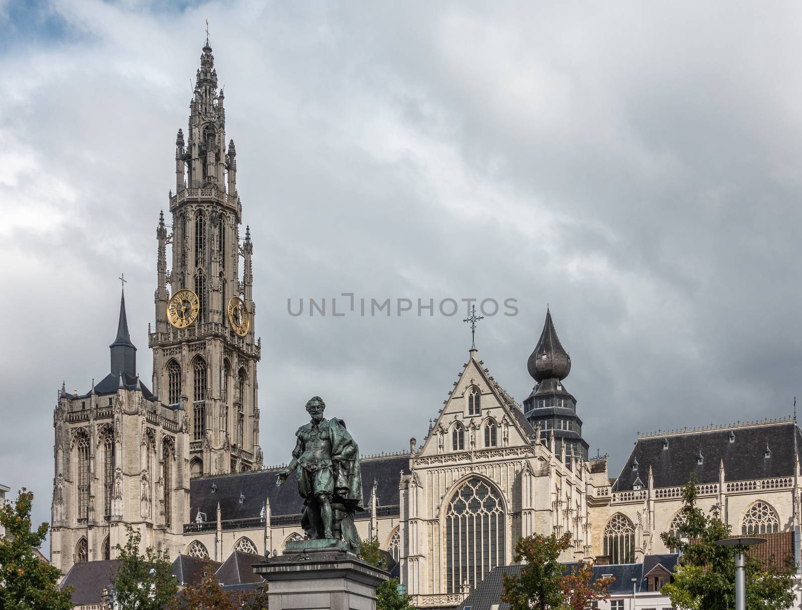 Antwerp, Belgium - September 24, 2018: Peter Paul Rubens bronze statue with towers, nave and chancel of Onze-Lieve-Vrouwe Cathedral of Our Lady in back under white cloudy sky.