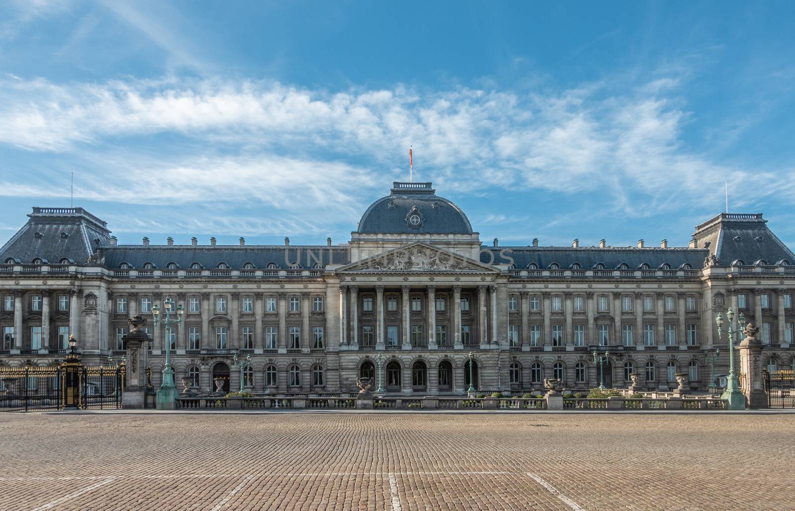 Brussels, Belgium - September 26, 2018: Brown stone, bluish roof Royal Palace in center of city under blue sky with some small white cloud. Front is wide road.