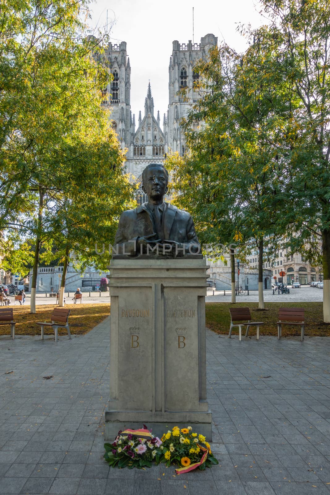 Brussels, Belgium - September 26, 2018: Bust Statue of King Boudewijn I in front of Cathedral of Saint Michael and Saint Gudula. Some green foliage around. Flowers up front.