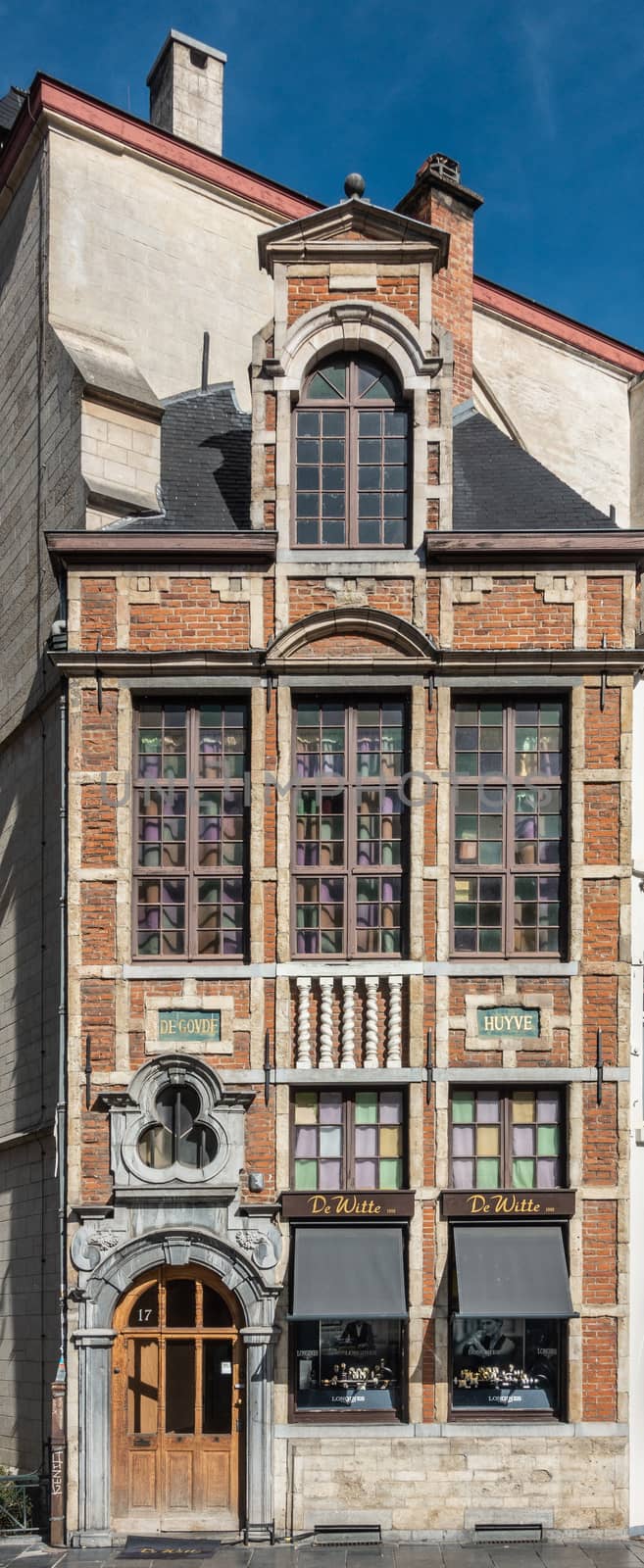 Brussels, Belgium - September 26, 2018: De Witte Jewelry store built against the Saint Nicolas Church with historic red brick facade and inscriptions and pillars under windows.