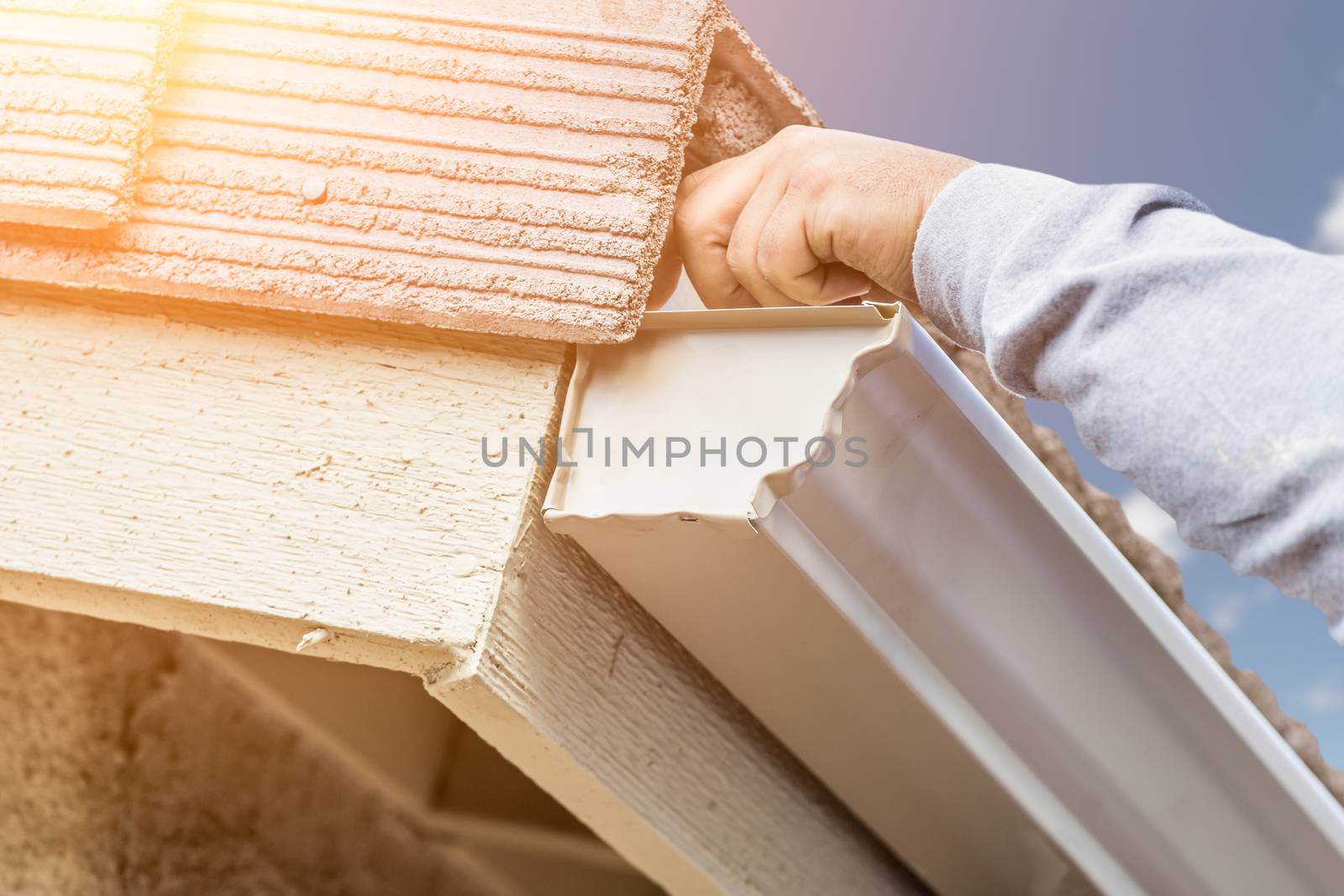 Worker Attaching Aluminum Rain Gutter to Fascia of House by Feverpitched