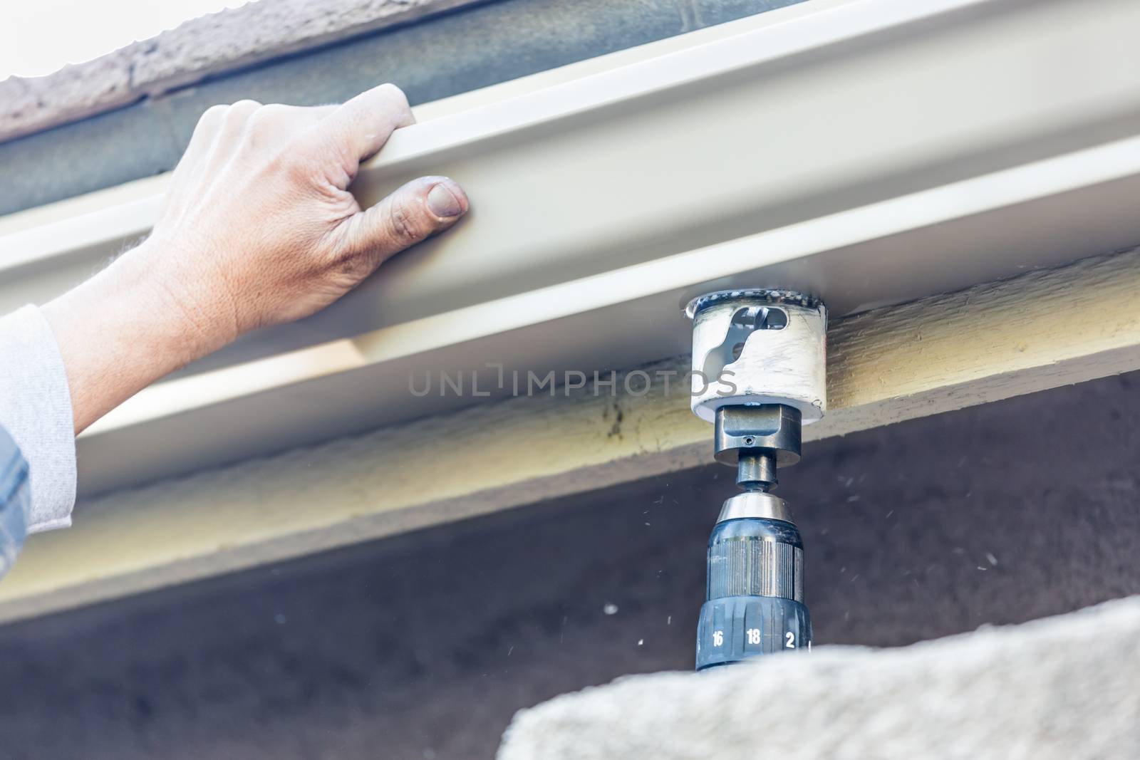 Worker Attaching Aluminum Rain Gutter to Fascia of House.