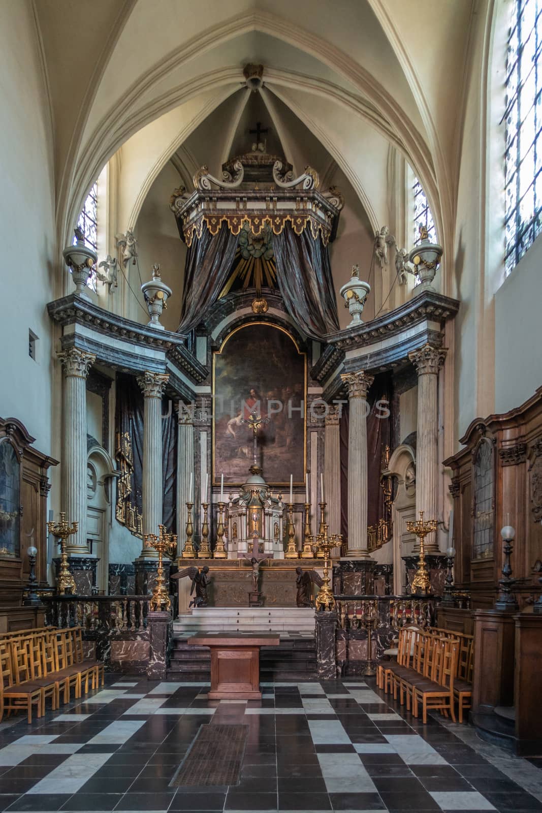 Brussels, Belgium - September 26, 2018: Inside Saint Nicolas Church. High altar with tabernacle, Jesus painting, candles, wooden sculptures, golden decorations.