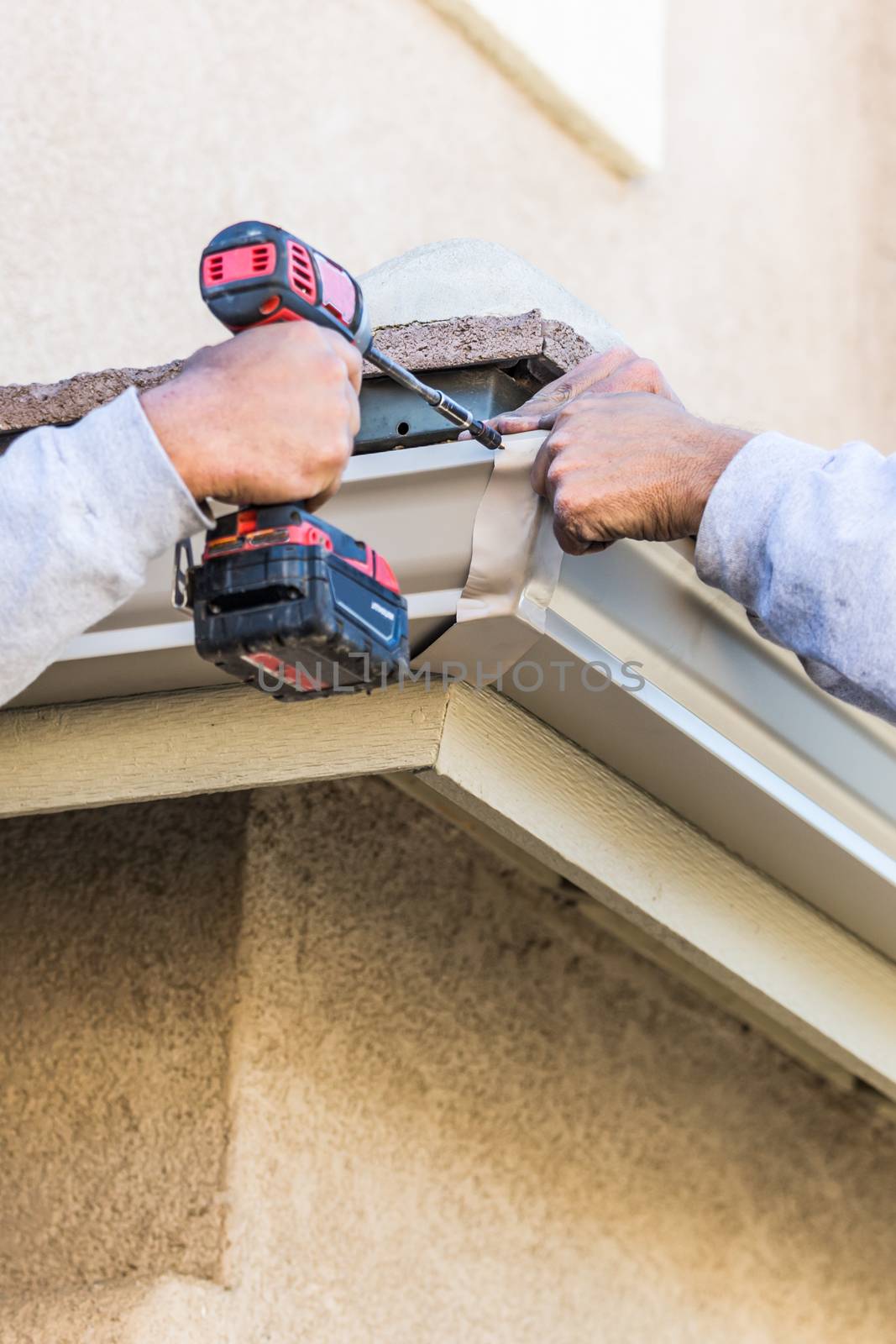 Workers Attaching Aluminum Rain Gutter to Fascia of House.