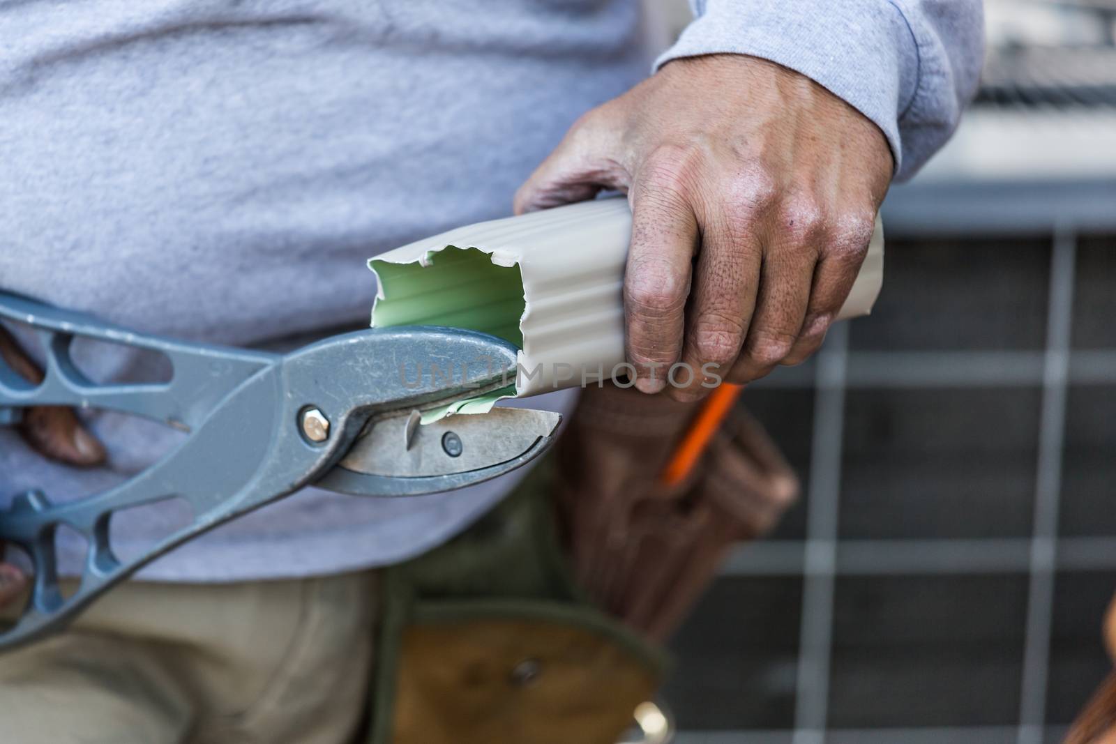 Worker Cutting Aluminum Rain Gutter With Heavy Shears by Feverpitched