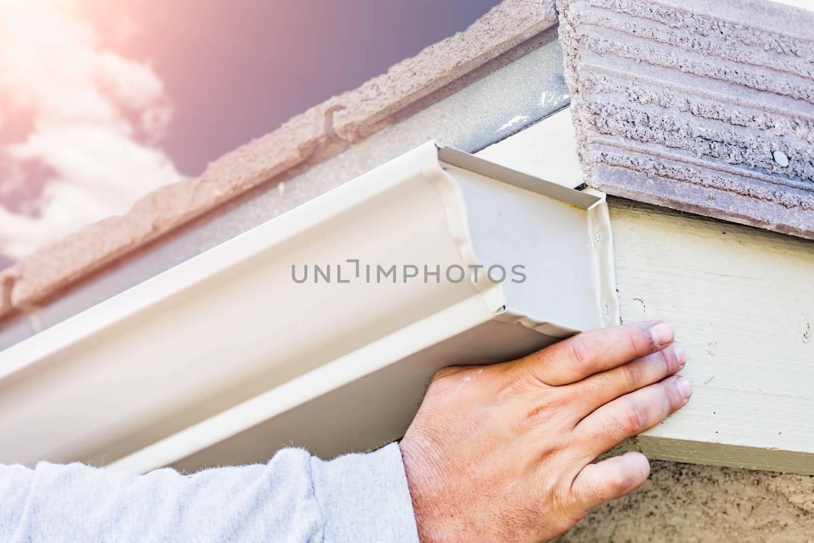 Worker Attaching Aluminum Rain Gutter to Fascia of House by Feverpitched