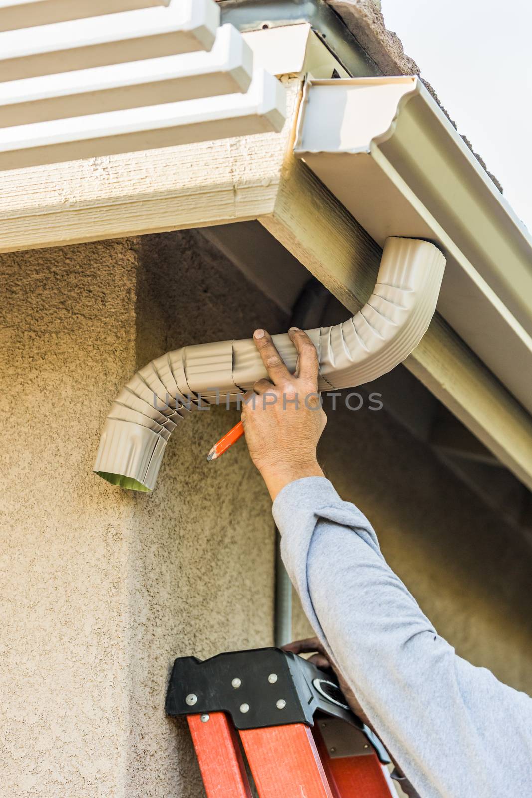 Worker Attaching Aluminum Rain Gutter and Down Spout to Fascia of House. by Feverpitched