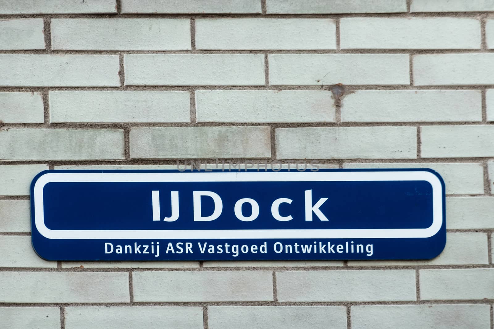 IJDOCk street sign against white brick wall, Amsterdam Netherlan by Claudine