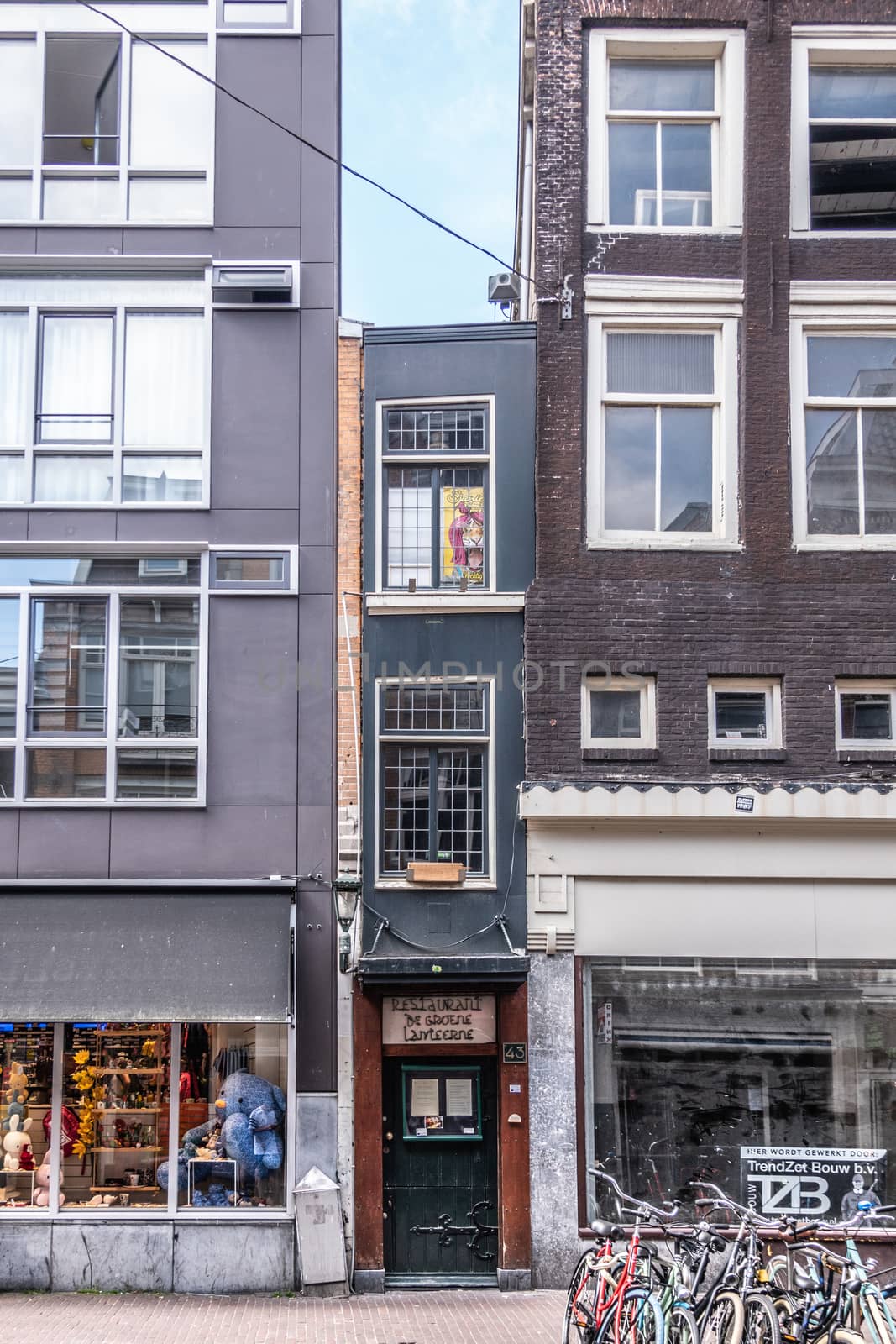 Amsterdam, the Netherlands - June 30, 2019: Smallest house and De Groene Lanteerne restaurant in Haarlemmerstraat squeezed between two other retail business buildings.