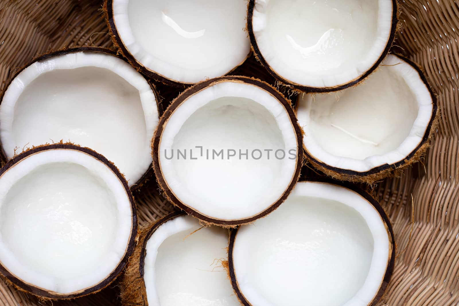 Top view of ripe coconuts in wicker basket.