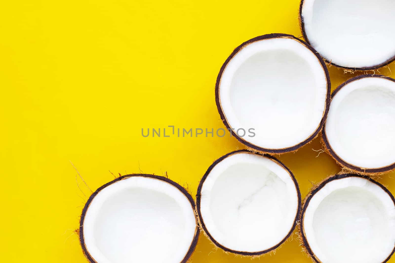 Half coconuts on yellow background. Copy space