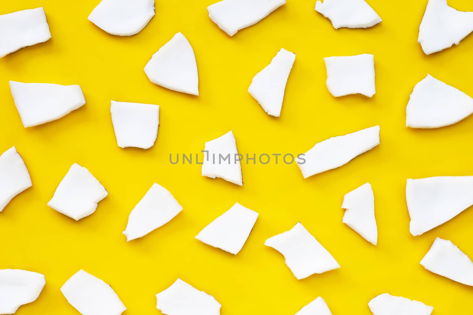 Coconut cut pieces on yellow background. Top view