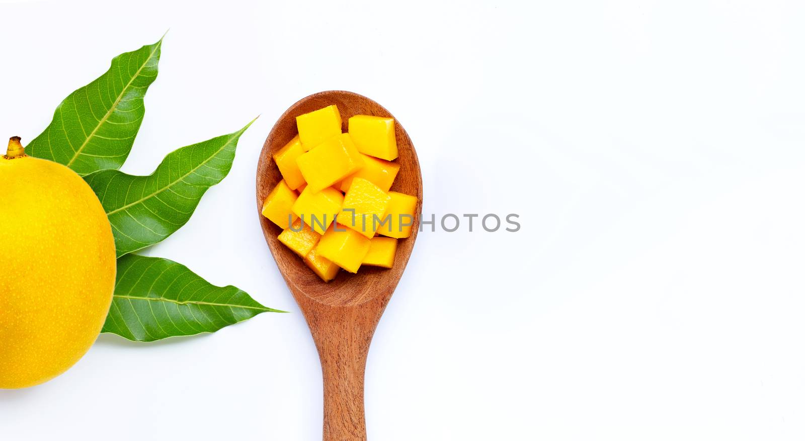 Sliced ripe mango cubes on wooden spoon on white background. Copy space