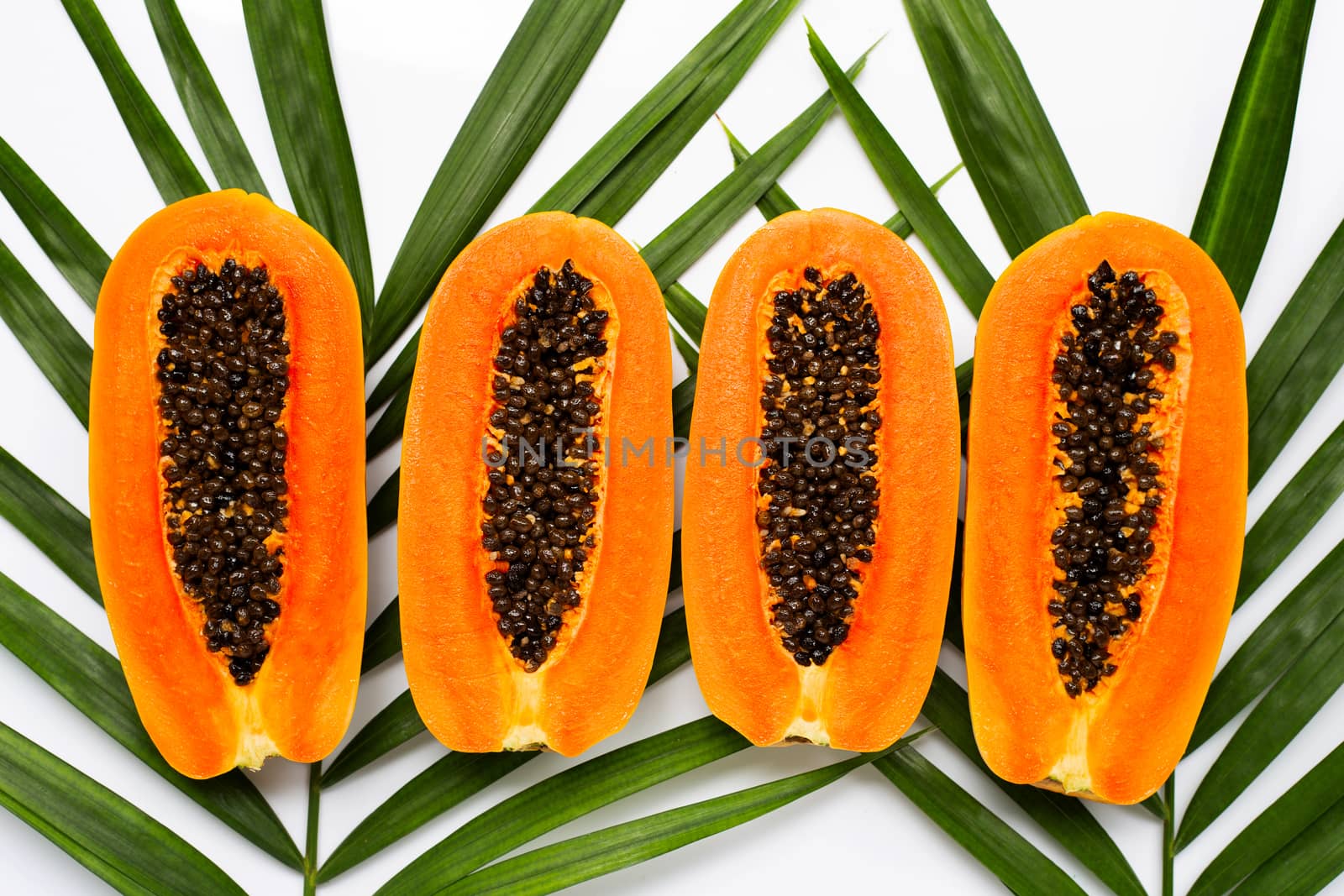 Half ripe papaya fruit on green leaves. Top view