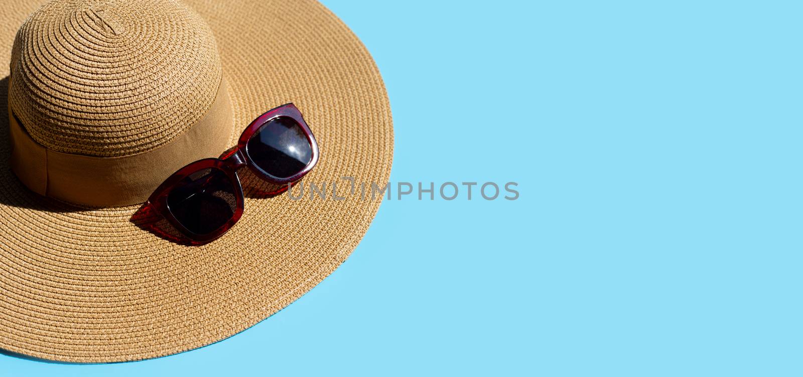 Summer hat with sunglasses on blue background. Enjoy holiday concept. Copy space