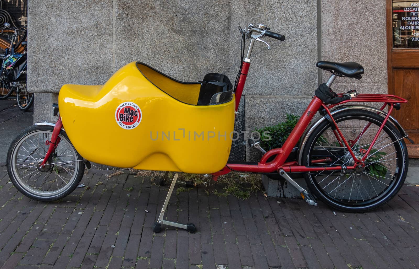 Amsterdam, the Netherlands - July 1, 2019: Closeup of parked bakfiets, front-trunk bike to transport a load or a child. Trunk in shape of yellow clog.