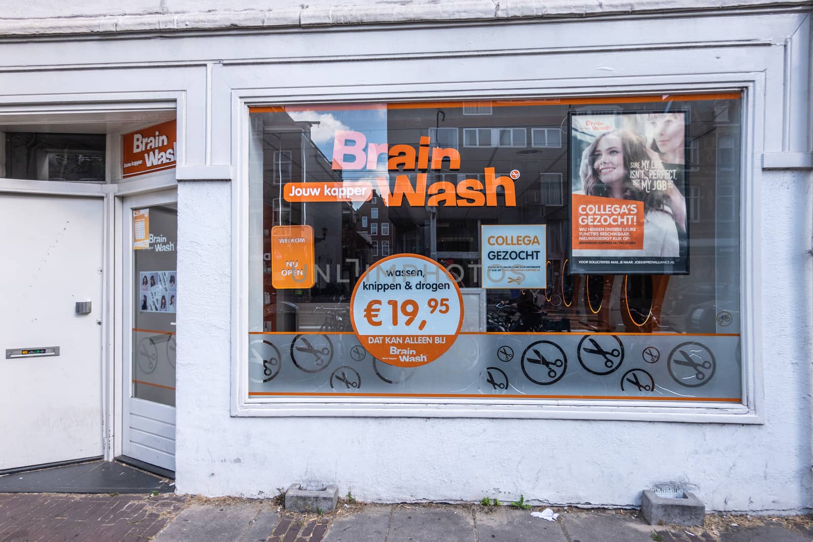 Amsterdam, the Netherlands - July 1, 2019: Facade of Brain Wash hair salon in white with orange letters on big display window.. Located in street called Overtoom.
