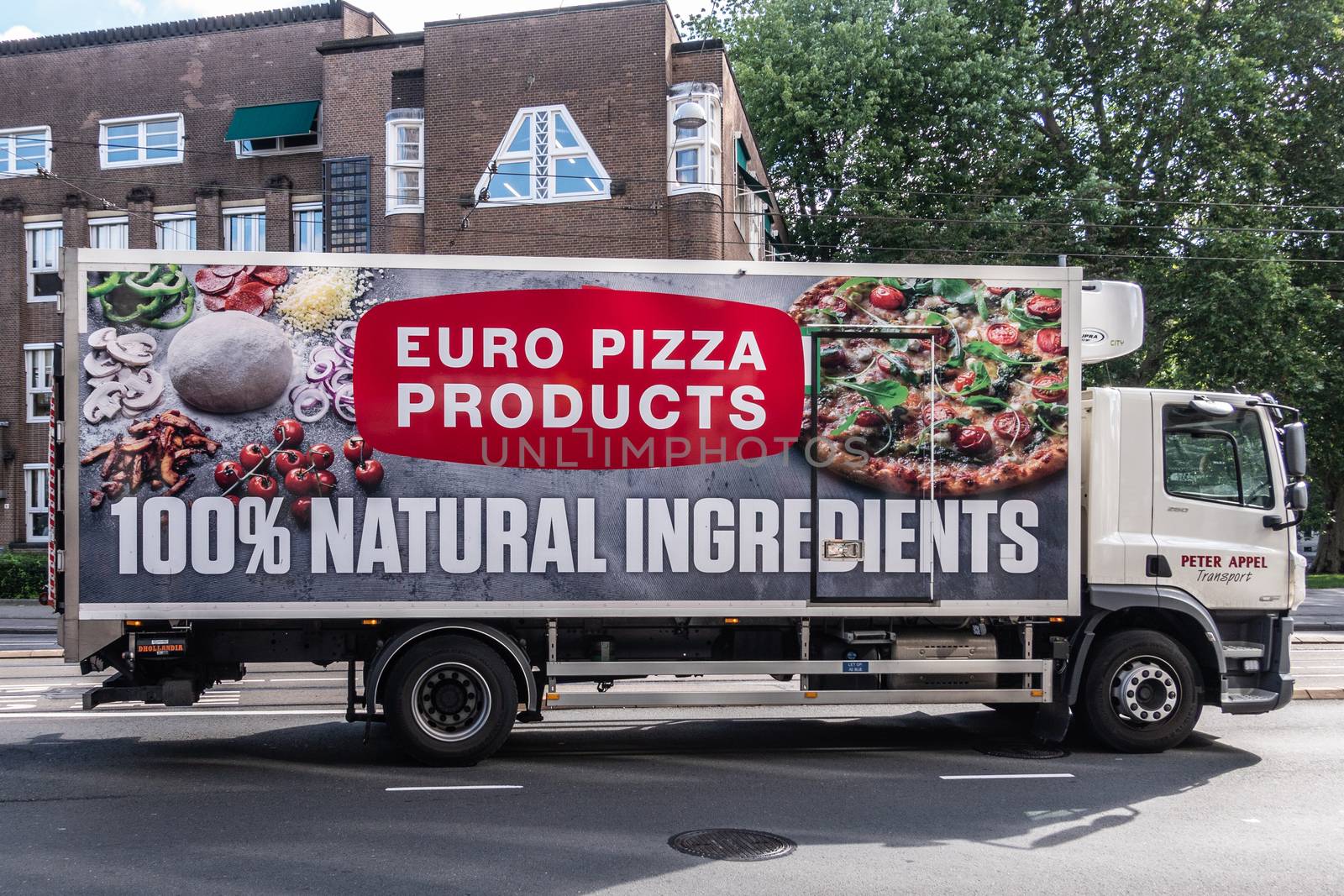 Amsterdam, the Netherlands - July 1, 2019: Euro Pizza producer and merchant deliver truck. Side plastered by huge photos of Pizza and ingredients. Street scene with green foliage.