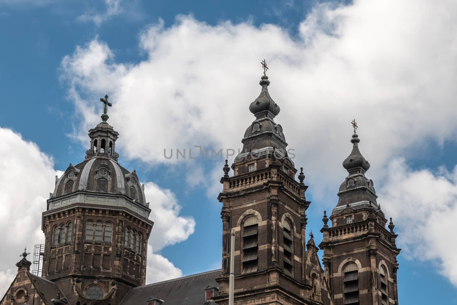 Amsterdam, the Netherlands - July 1, 2019: Red brick with white trim towers and roof structure of Basilica of Saint Nicolas under cloudscape.