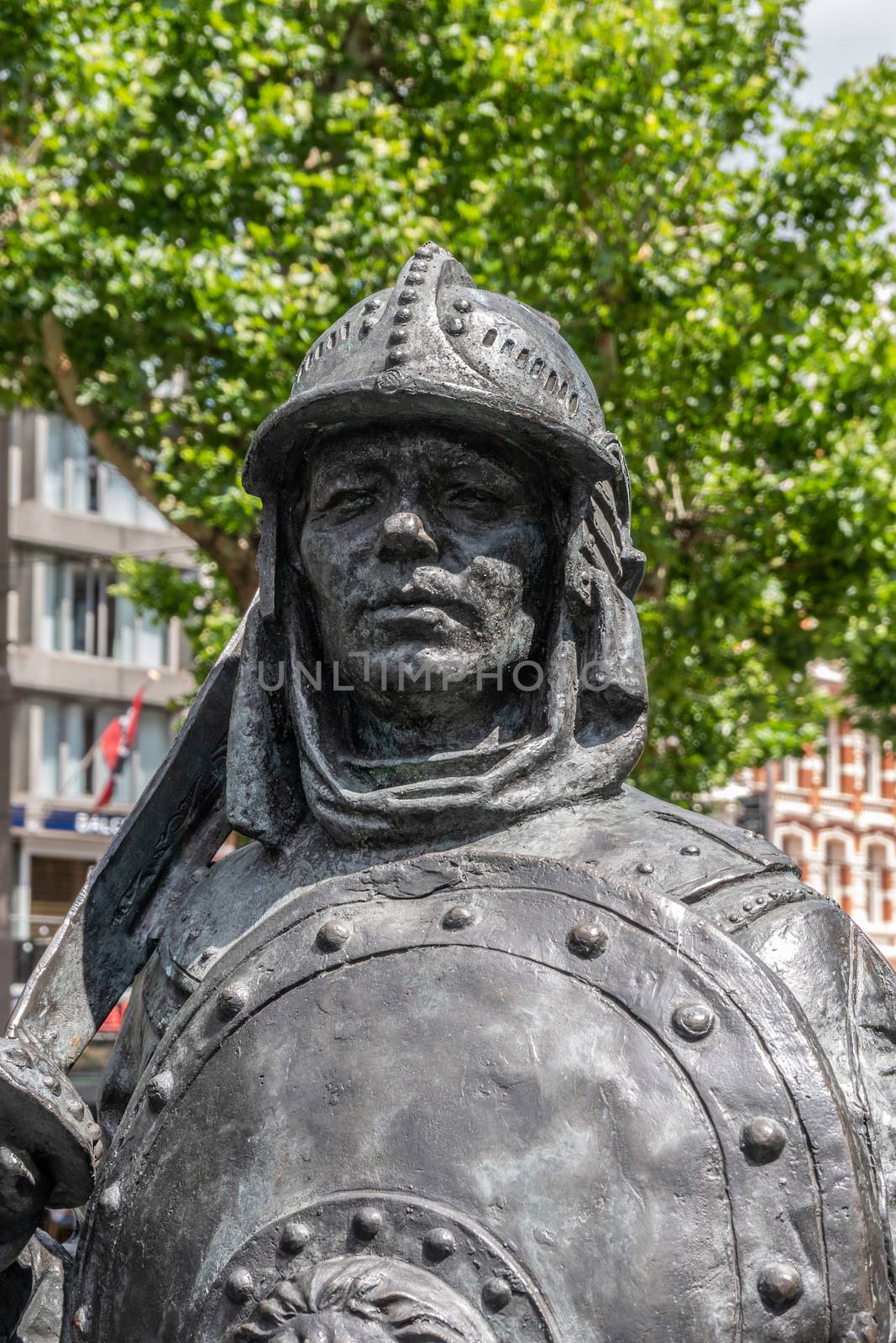Amsterdam, the Netherlands - July 1, 2019: De Nachtwacht compostion of statues on Rembrandtplein. Closeup of bust of one of several shield and sword carrying figures against green foliage and buildings.