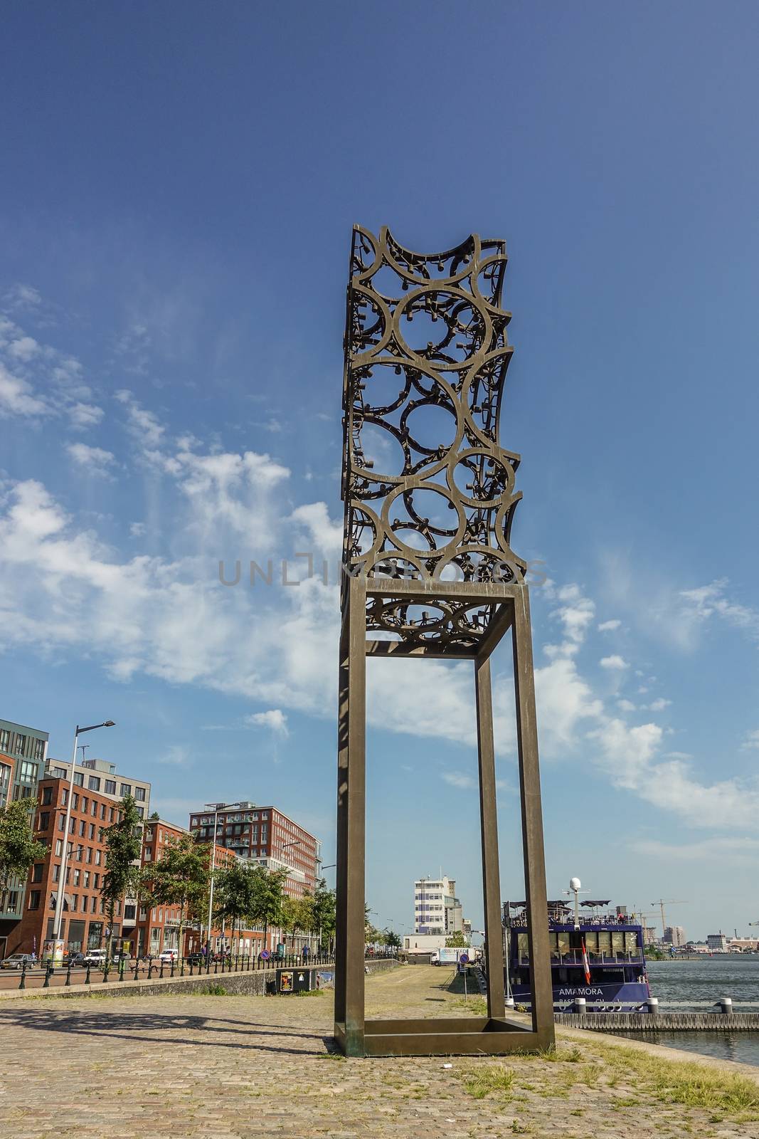 Amsterdam, the Netherlands - June 30, 2019: Tall rusted artwork, sculpture of metal circles welded together and set against blue sky with some white clouds on IJdok.