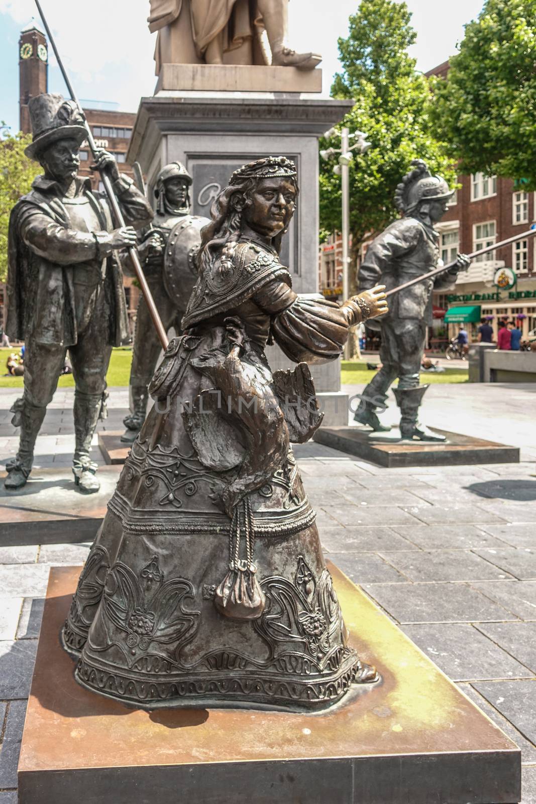 Amsterdam, the Netherlands - July 1, 2019: De Nachtwacht compostion of statues on Rembrandtplein. full body of sole female figure with other statues in back.