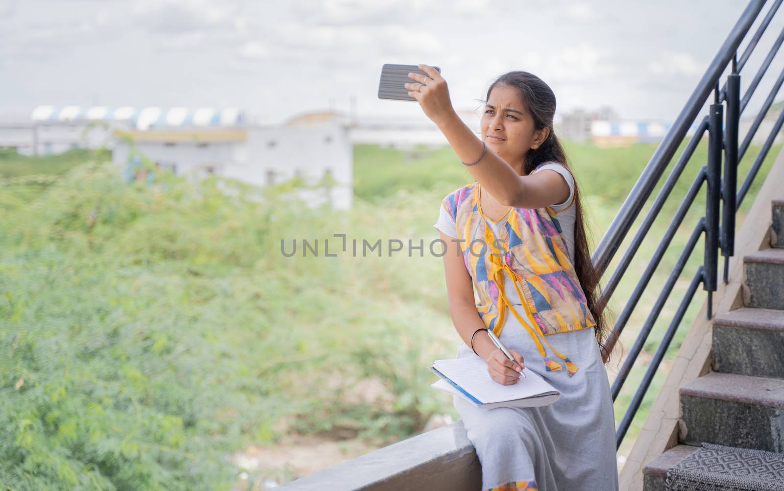 College girl outside home watching online class due to slow internet connection - concept of network issue at remote places and problem of virtual class or distance learning during pandemic. by lakshmiprasad.maski@gmai.com