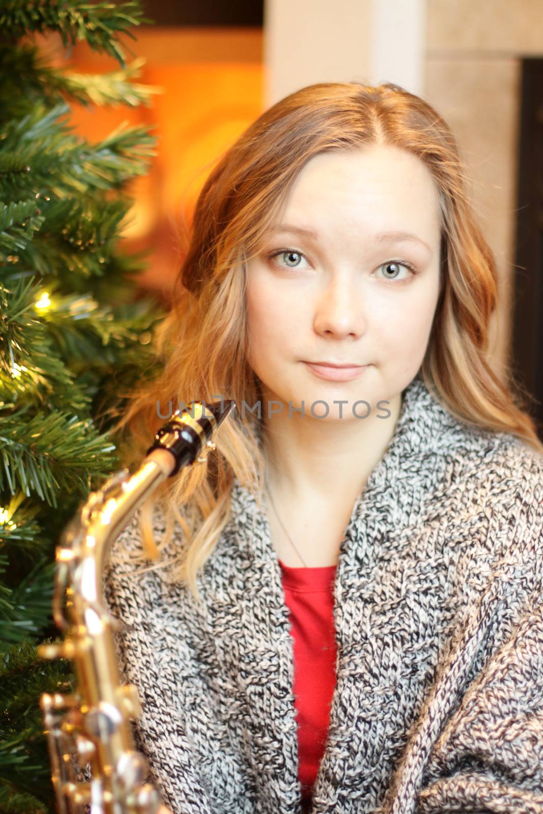 Portrait of the beautiful musician girl with saxophone. Christmas.
