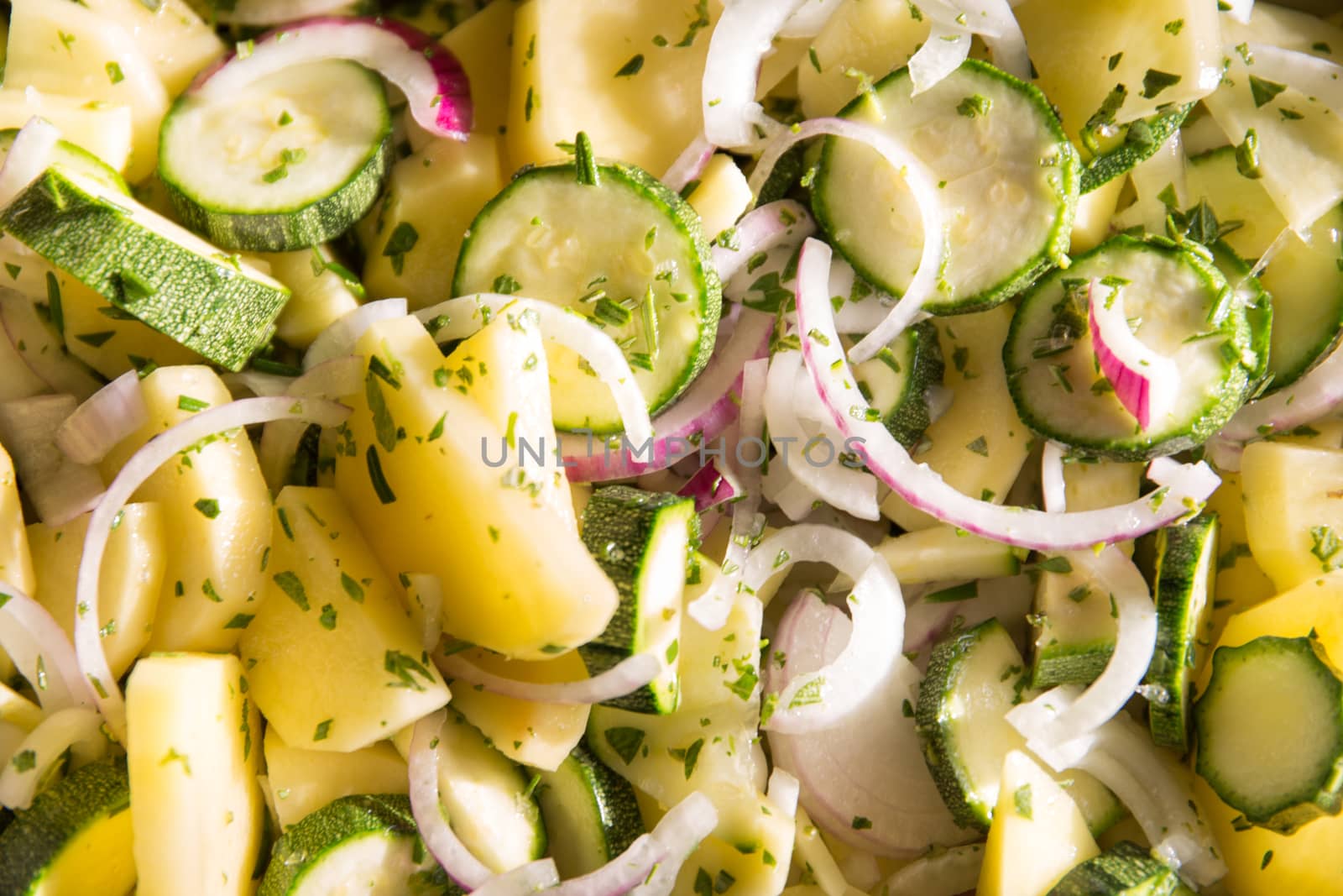 Vegan food: close-up of pan of raw vegetables sliced ​​like ratatouille with courgette, potatoes, onions and seasoned with sage, oregano and rosemary before being cooked by robbyfontanesi