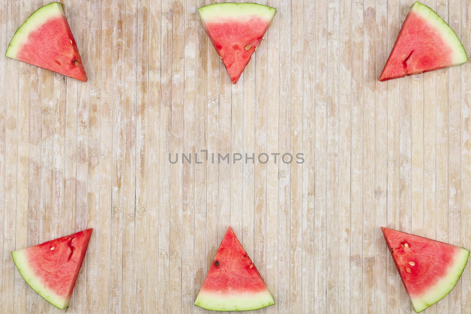 Triangular slices of watermelon that form geometric games for copy space on a light wooden background by robbyfontanesi