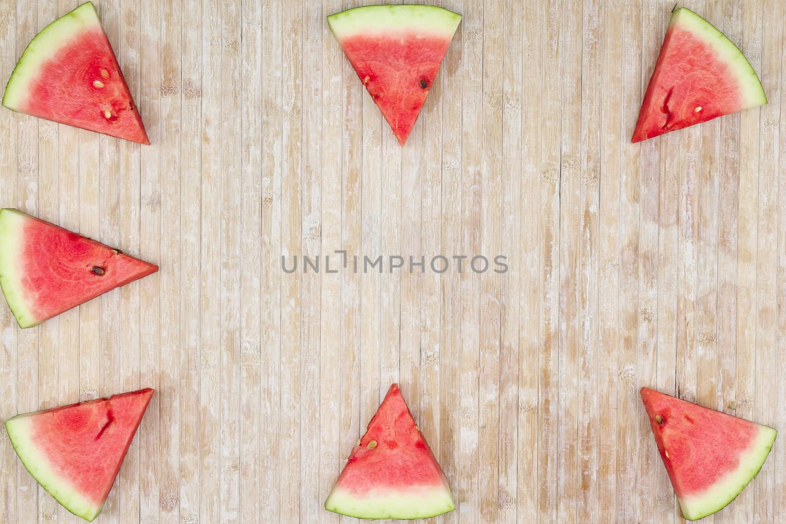 Triangular slices of watermelon that form geometric games for copy space on a light wooden background by robbyfontanesi