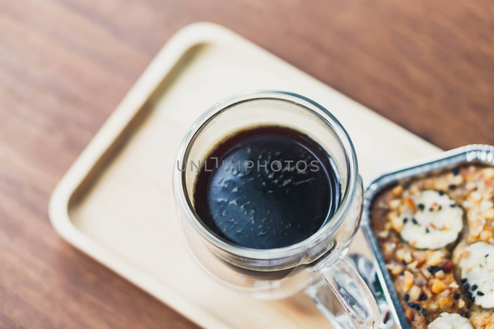 Closeup glass of hot americano coffee and cake on wood table, selective focus, vintage tone